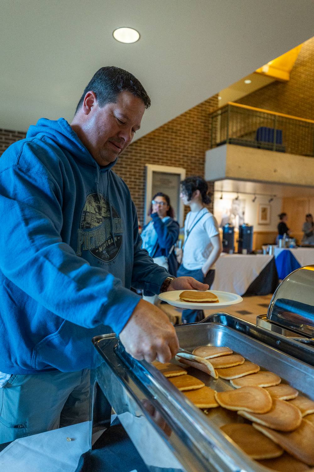 Person grabbing pancakes from warming dish in Kirkhof Center lobby.